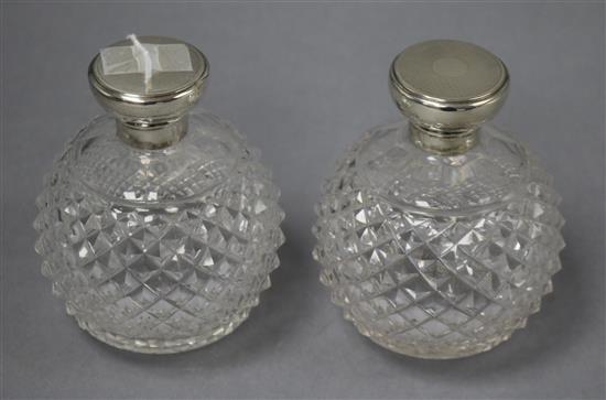 A pair of George V engine turned silver topped cut glass globular scent bottles, GW, London, 1920, 12.5cm.